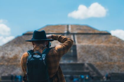 Man in black hat capturing Teotihuacán pyramid with camera and backpack.